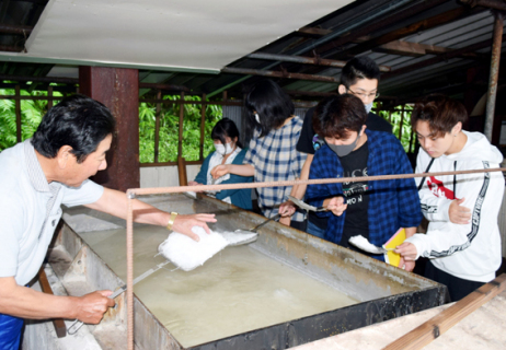 高橋さん（左）の指導で平釜から塩をすくう学生たち