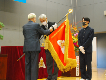 佐藤委員長（左）が百瀬校長に新調した校旗を贈呈