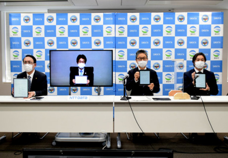 電子署名したタブレット端末を披露する（左から）丸山市長、本間社長、渡会支店長、神田学長