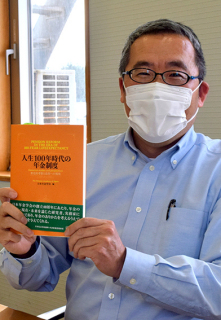 日本年金学会創立40周年記念書籍を手にする阿部教授