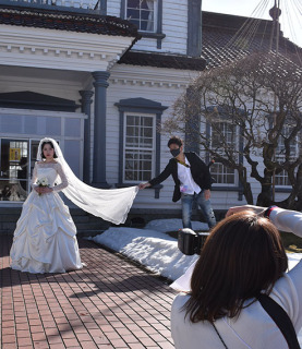 絹産業にゆかりのある旧西田川郡役所前でシルクのドレスに身を包んだ生徒が撮影に臨んだ