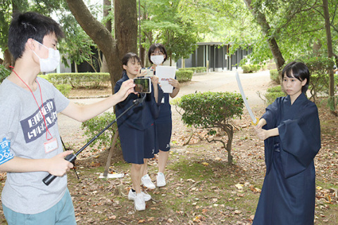 鶴岡公園内で動画を撮影する高校生たち＝9日午前