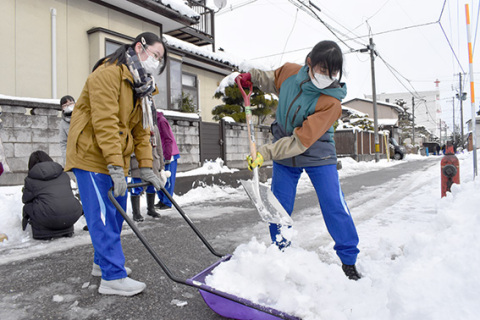 協力して道路の除雪を行う生徒たち