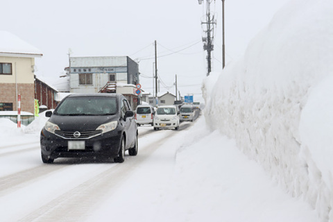 路肩に積もり重なった「雪壁」。優先道路に進入する際、ドライバーの視界を防いでいる＝7日、鶴岡市苗津町の県道（通称・羽黒街道）で