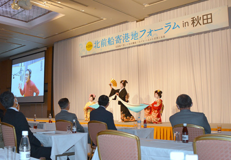 レセプションで、映像参加の五木さん（左）の歌に合わせ、華麗な舞を披露する酒田舞娘＝19日夜、秋田キャッスルホテル