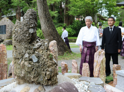 羽黒山頂の出羽三山神社境内に建立された「さざれ石」。寄進した深川さん（右）と宮野宮司