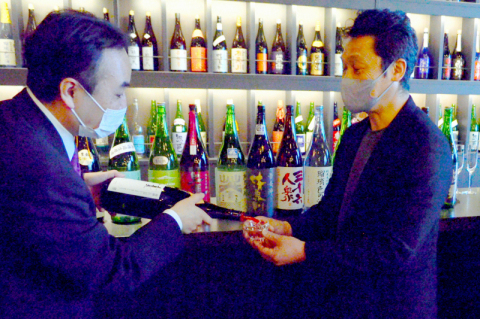 解説を交えながらおすすめの日本酒を注ぐ高橋社長（左）
