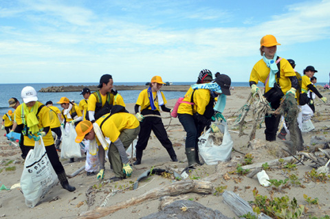 笑顔で海岸清掃に取り組む学生たち＝31日