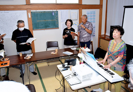 佐藤事務局長（右）の伴奏に合わせ声をそろえる参加者たち