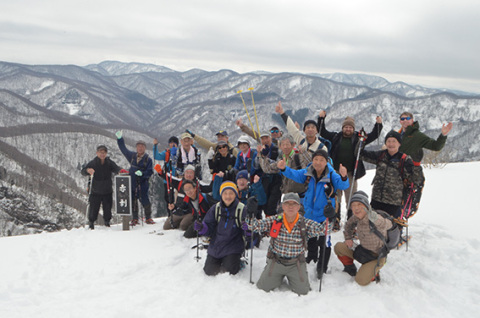 神室連峰をバックに記念撮影する参加者