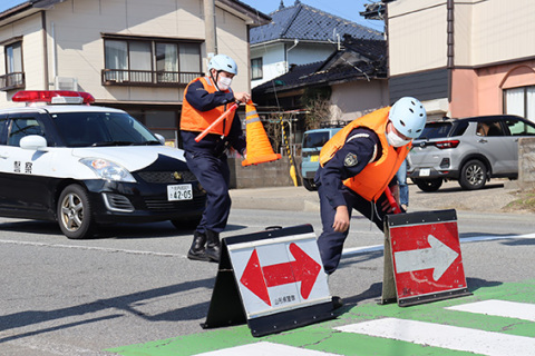 停電で信号機が止まった十字路交差点で交通整理の対応訓練を繰り広げる鶴岡署員＝鶴岡市湯野浜
