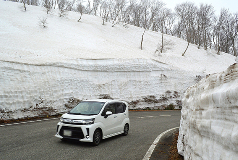 高い雪の壁を見上げるようにしてドライブ＝25日、秋田県境付近