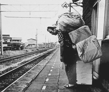 藤島駅のホームで大きな荷物を背負って帰りの列車を待つ五十嵐さん＝提供・五十嵐富美恵さん