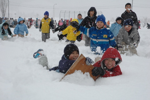 雪上に飛び込み、正解のカルタをゲットする児童たち