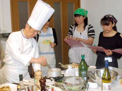 太田シェフ（左）の指導でガス器具を上手に使い、女性たちがフランス料理3品に挑戦した