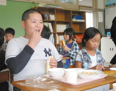 東平田小の4年生たちが酒田女鶴の米粉を50％混ぜたパンをおいしそうにほお張った