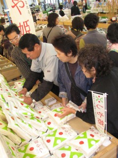 先行販売に大勢の買い物客が訪れ、つや姫の新米を手にした＝10日、鶴岡市の産直こまぎ