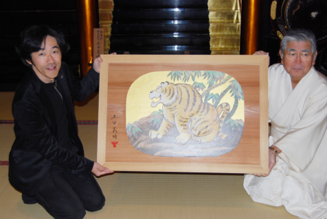 土田さん（左）が来年の干支・寅を描いた大絵馬を緒方宮司に手渡した