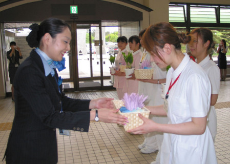 長崎さん（左）が3病院の看護師にスズランの鉢植えとしおりを贈った