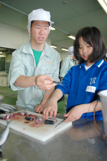 加茂小の児童たちが高校生から教わりながら、サンマの缶詰作りを体験