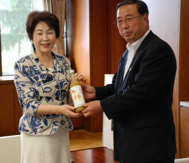 黒井組合長（右）が柿ジュースの試作品を吉村知事に手渡した