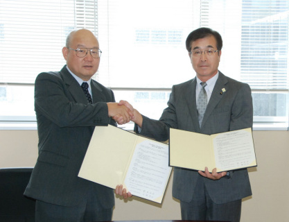 協定書に署名し握手を交わす安田学部長（左）と百瀬校長