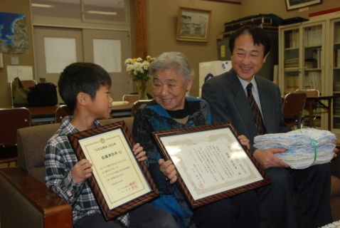 ひ孫の望武君（左）、遠藤校長（右）に挟まれ、笑顔の佐藤さん