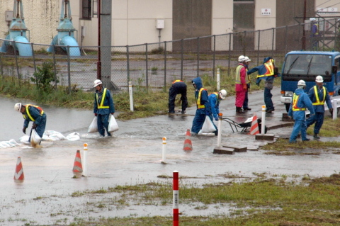 全面通行止めとなった国道7号と47号が交差する広田インターチェンジで、土のうを積む作業員たち＝24日午前10時半ごろ