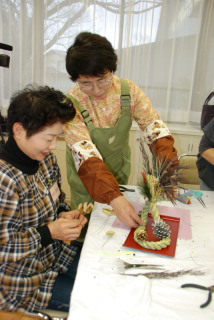 長堀さん（奥）のアドバイスでモダンなしめ縄飾りを作る参加者