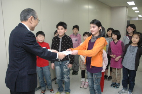 酒田こども歌舞伎の会のメンバーたちが中村副会長（左）に義援金を手渡した