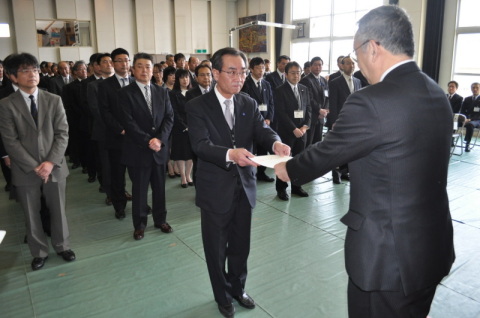 2012年度が実質的にスタート。榎本鶴岡市長（右）が異動職員に辞令を手渡した＝鶴岡市