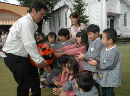 大高理事（左）が園児たちにお化けカボチャをプレゼントした＝29日、マリア幼稚園