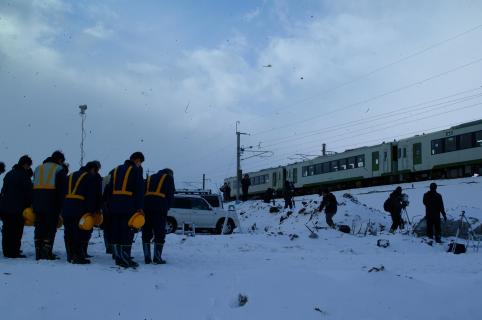 ＪＲ羽越本線の運転再開を前に、試運転の列車が脱線事故現場を通過。犠牲者に黙とうをささげるＪＲ東日本の職員＝18日午前9時半ごろ