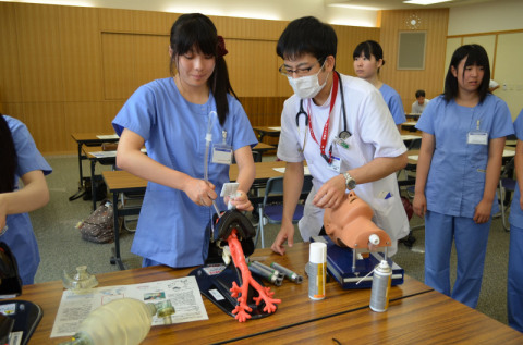 気管挿管を模擬体験する高校生（左）