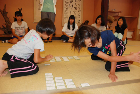 デモンストレーションで小学生が素早く札を取る様子に、受講生たちが注目した