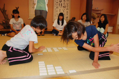 デモンストレーションで小学生が素早く札を取る様子に、受講生たちが注目した