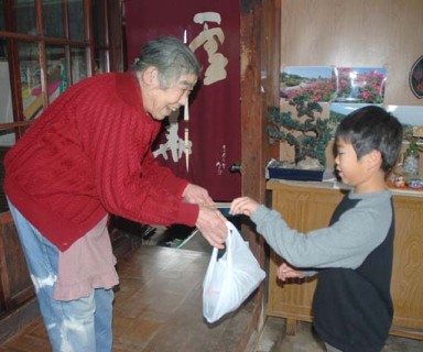 斎小の3年生が一人暮らしのお年寄りを訪問し、そばを渡した