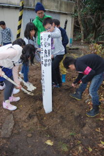 由良小の4年生6人が協力しながら土を掛けタイムカプセルを埋めた
