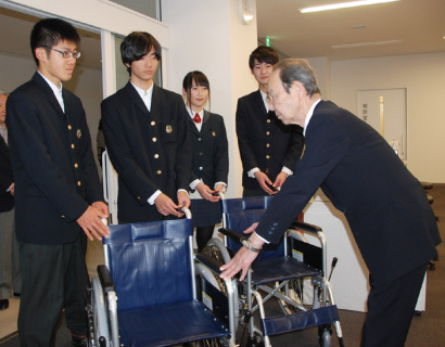 鶴岡東高の新旧生徒会メンバー（左）が鶴岡市社協の難波会長に車椅子2台を引き渡した