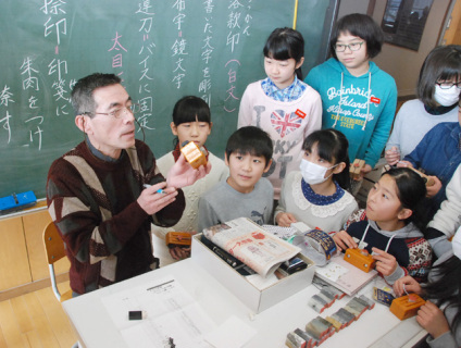 印章彫刻マイスターの永井さんの匠の技を間近で観察する児童たち