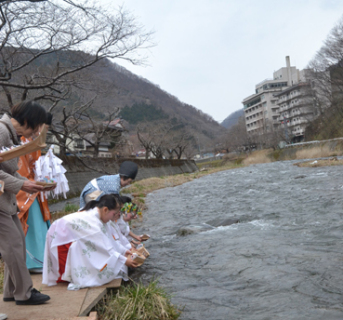 多くの観光客が願いを込めて折った紙雛を巫女装束の子供たちが川に流した
