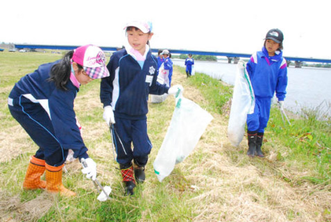 最上川河川公園でごみを拾う亀ケ崎小の4年生たち