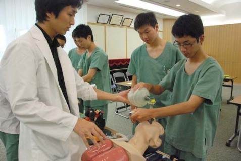 医師の指導を受けながら気管挿管に取り組む高校生たち