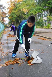 学校周辺の道路で落ち葉を集める泉スポ少の子供たち