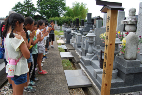 境内の齋藤の墓地で手を合わせる長沼小の児童たち