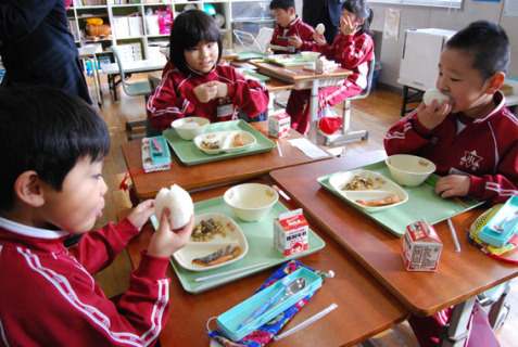 大きなお口でパクッ。学校給食発祥の地・鶴岡で「おにぎり給食」が実施された＝2日、京田小