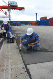 酒田港国際ターミナルのガントリークレーンのレール脇にトラップを設置する作業員＝22日午前