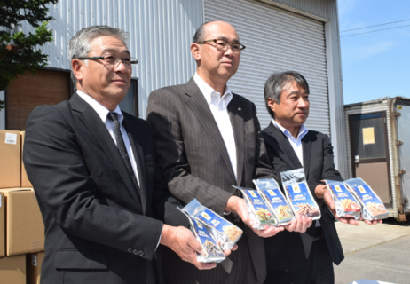 輸出される「かりんと百米」７種を持つ（左から）佐藤社長、原田町長、二上副社長