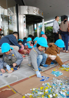 鶴岡Ｄａｄａのグランドオープンを前に、幼稚園児たちが玄関前の床にタイルで絵を描くワークショップを楽しんだ＝24日