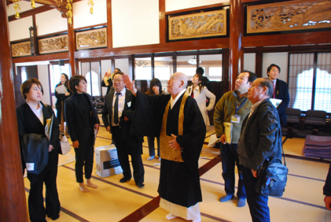 心光寺で丸山住職（中央）の解説を聞く参加者たち